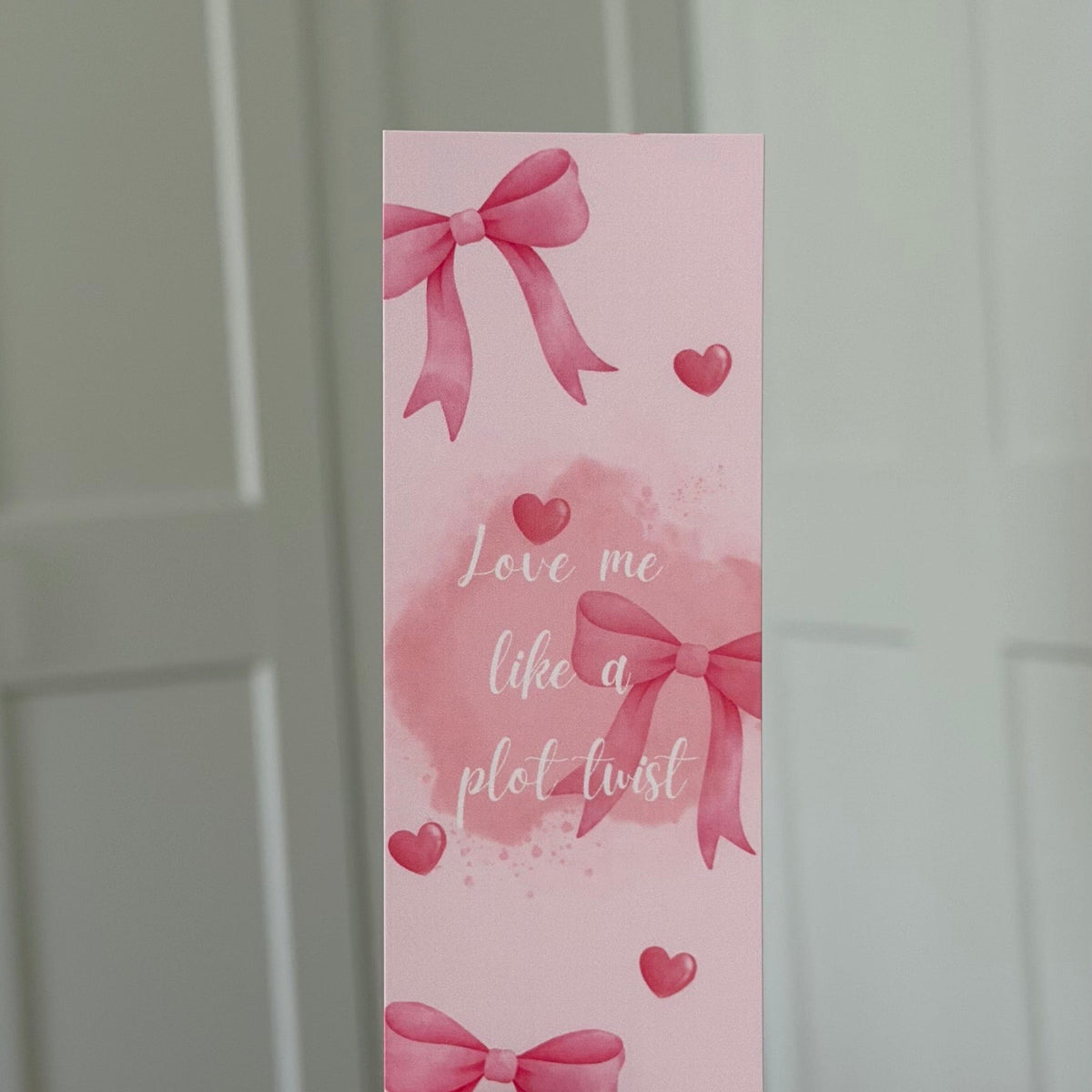 Lesezeichen „Love me like a plot twist“ mit rosa Schleifen